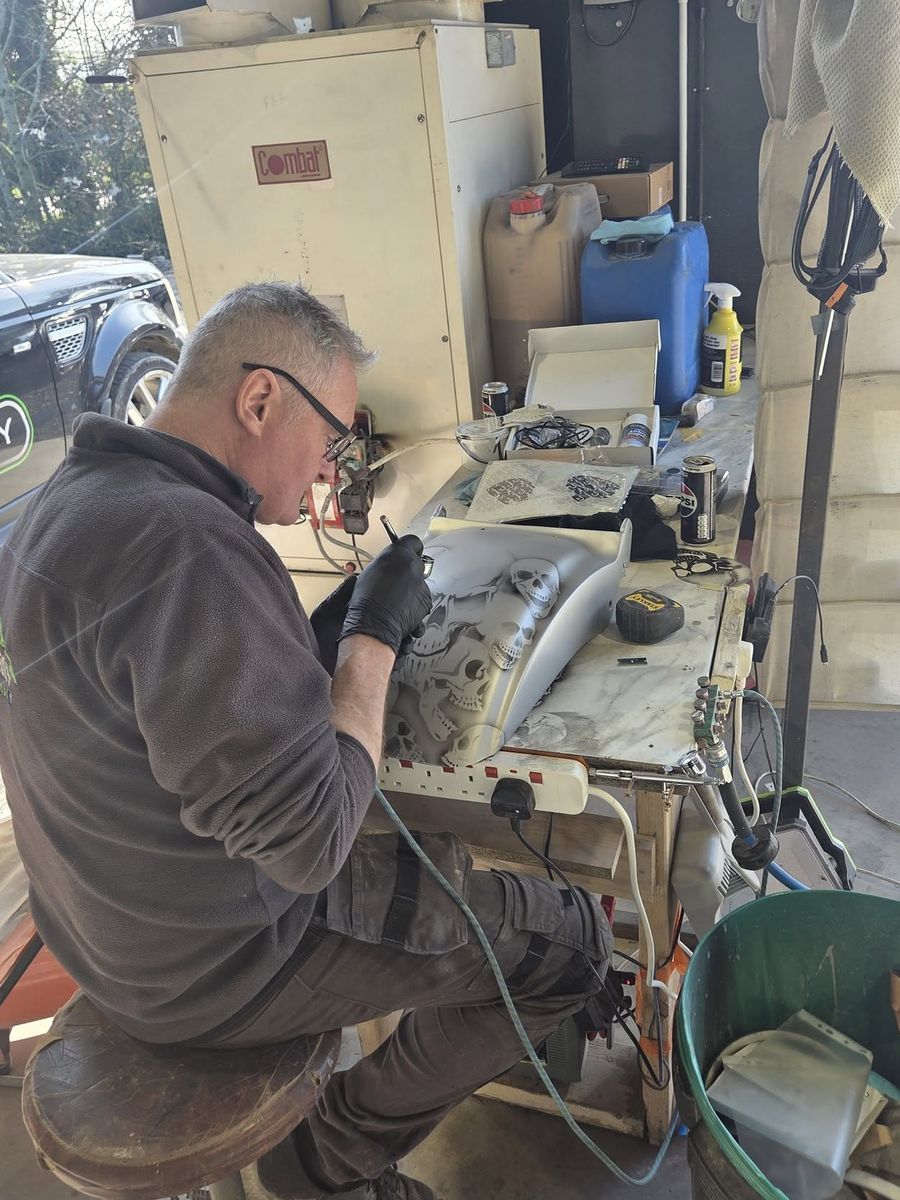 Airbrushing a skull design onto a motorcycle fender by hand
